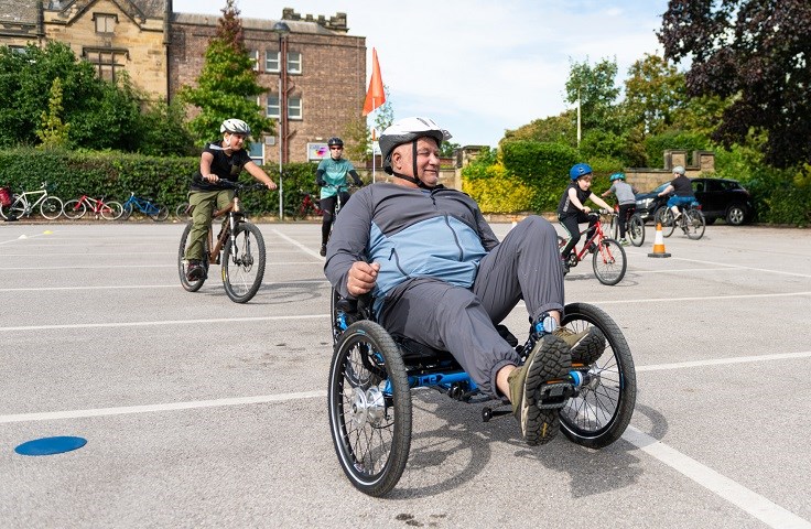 Man on 3 wheeled bike pedaling in seated position